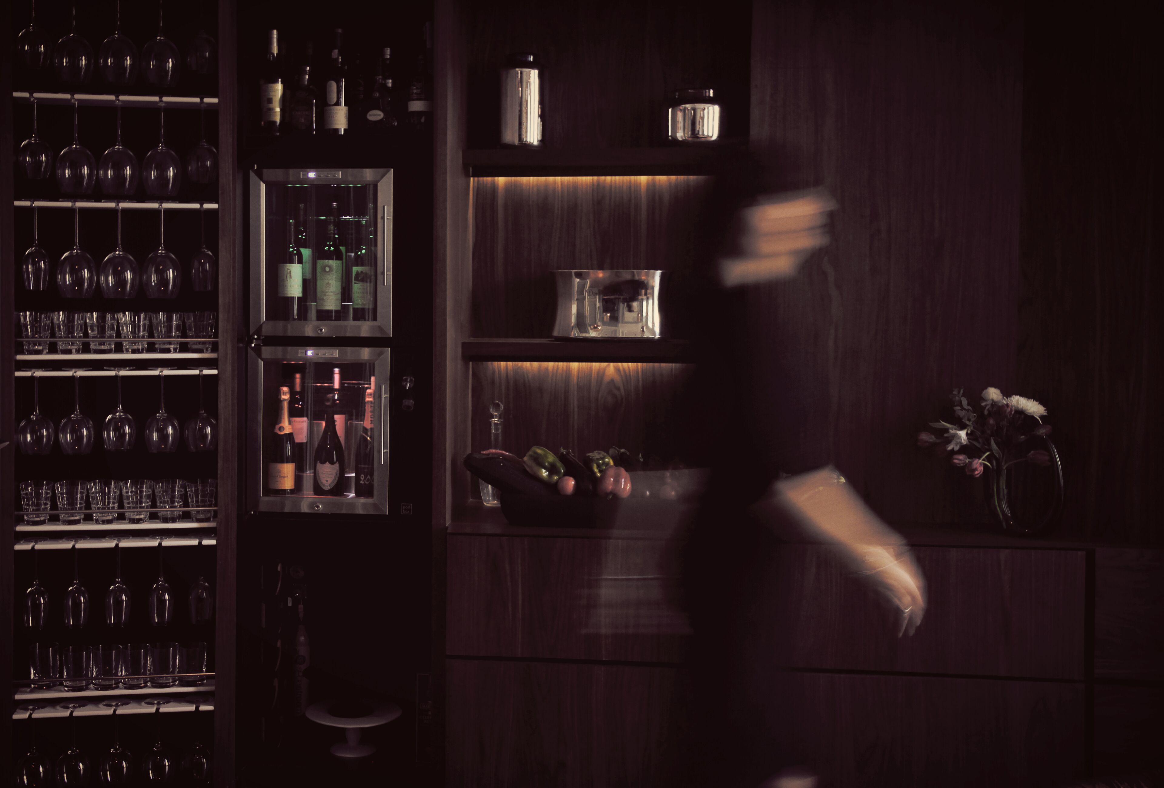 Una zona de bar con estanterías llenas de botellas de vino y copas.
