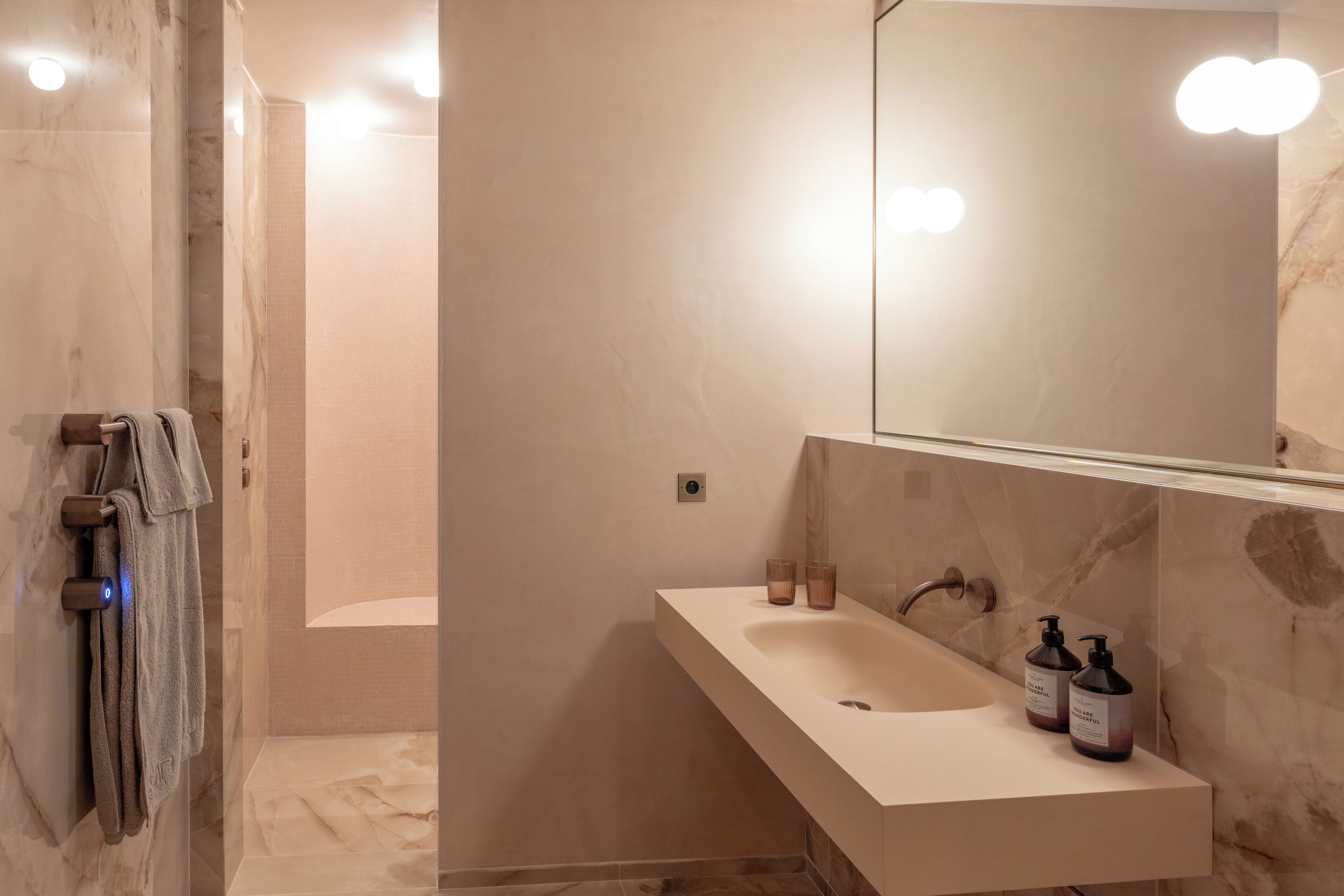 A modern bathroom with a marble sink, a large mirror, and a shower area.