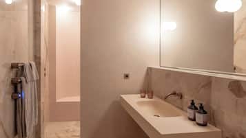 A modern bathroom with a marble sink, a large mirror, and a shower area.