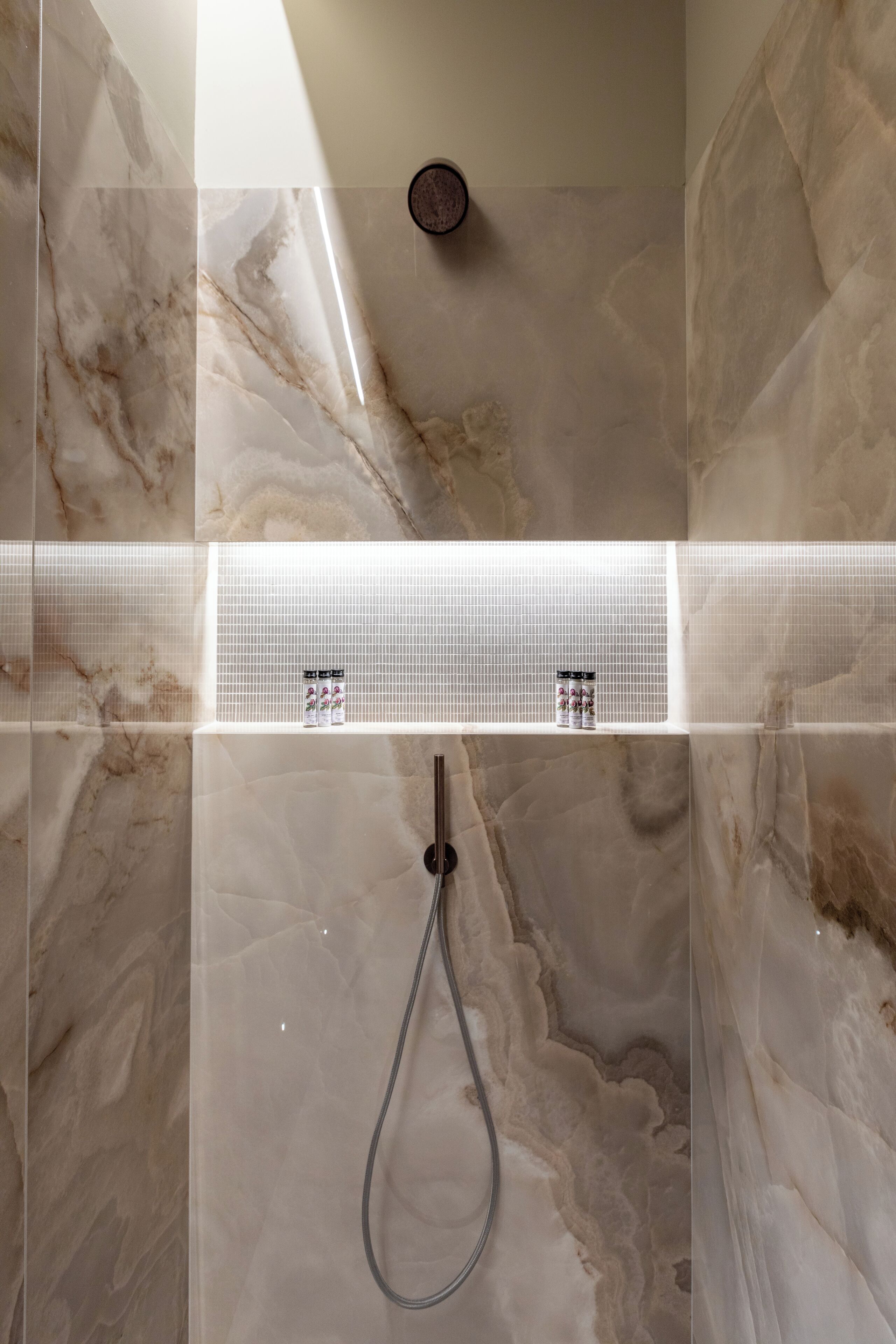 A bathroom with marble walls and a shower area.