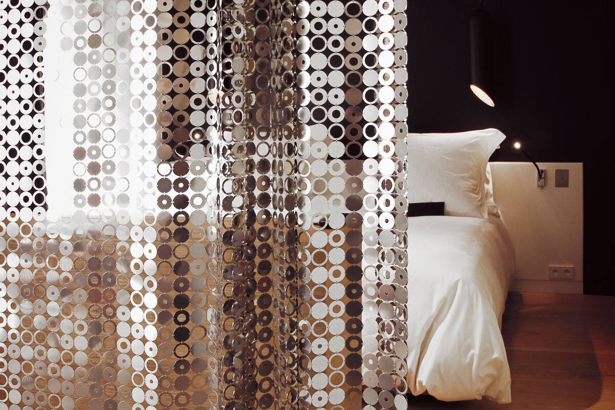 Un dormitorio con cama, mesita de noche y lámpara colgante.