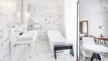 Ein modernes Badezimmer mit einem weißen Marmorwaschbecken, einer freistehenden Badewanne und einer Duschkabine aus Glas.
