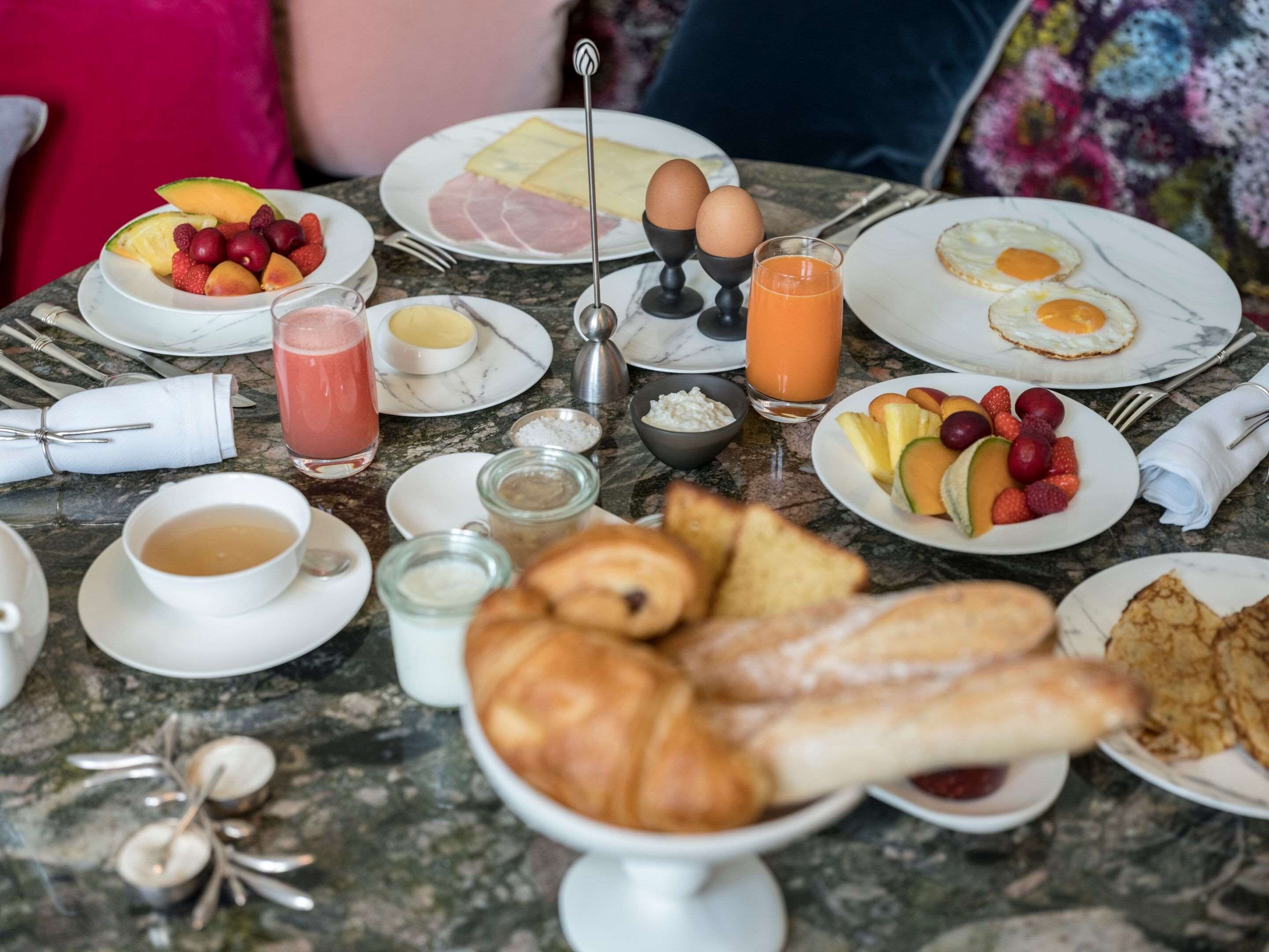 Una mesa de desayuno con platos de huevos, tostadas, fruta y jugo.