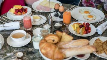 Una mesa de desayuno con platos de huevos, tostadas, fruta y jugo.