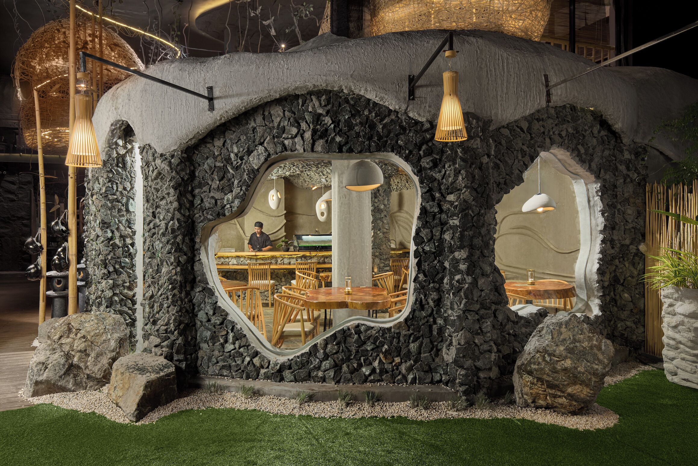 A restaurant with a stone facade and mirrored windows, featuring wooden tables and chairs.