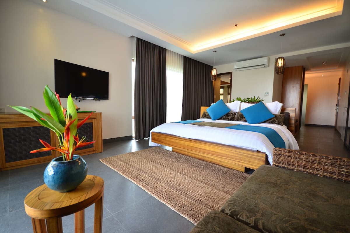 Een moderne hotelkamer met een groot bed, een televisie en een kamerplant.
