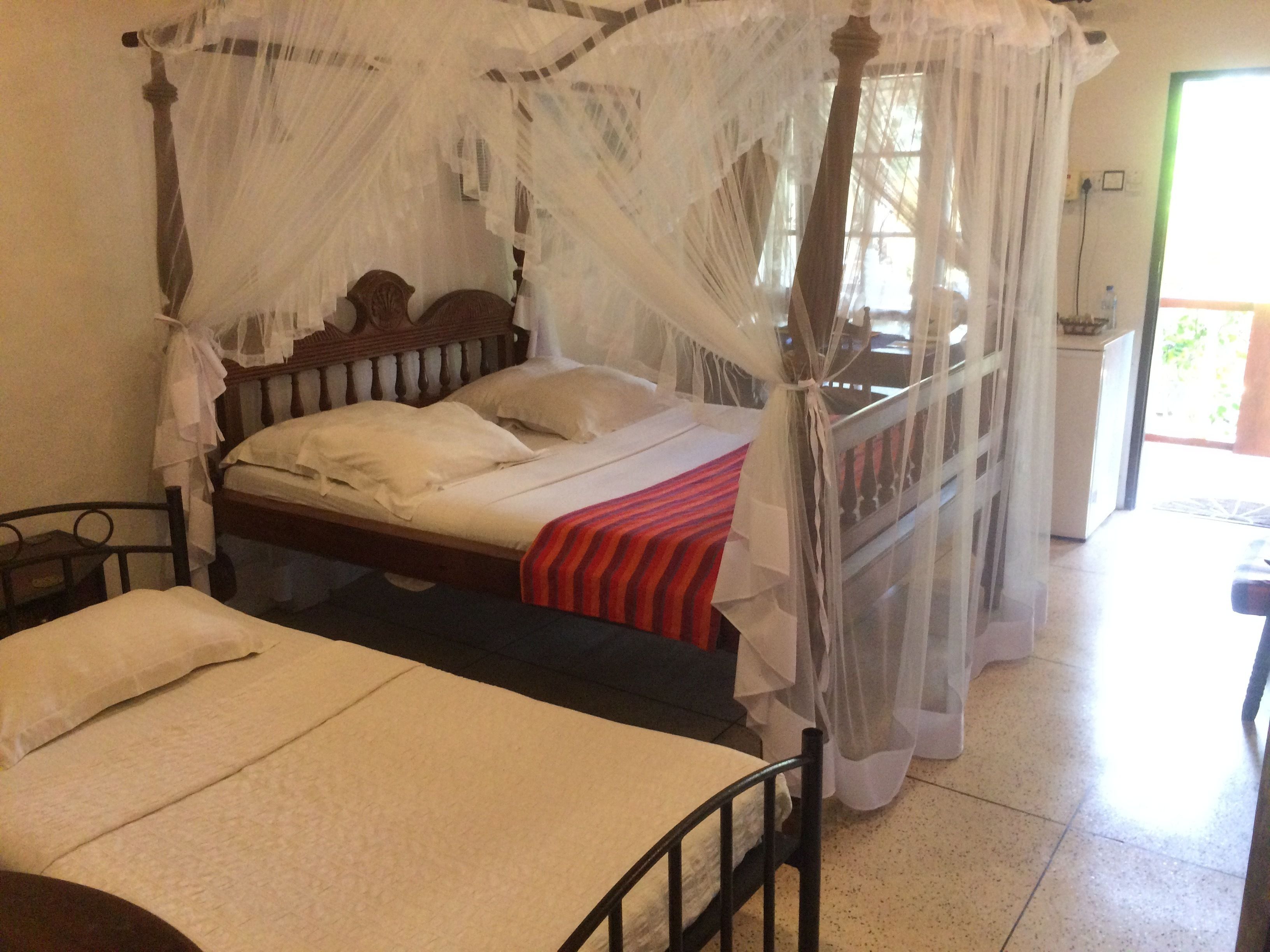 Una habitación con una cama con dosel, una cama individual y una mesita pequeña.