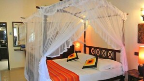 A bed with a canopy, a bedside table, and a nightstand. - Hotel Flower Garden (Unawatuna)