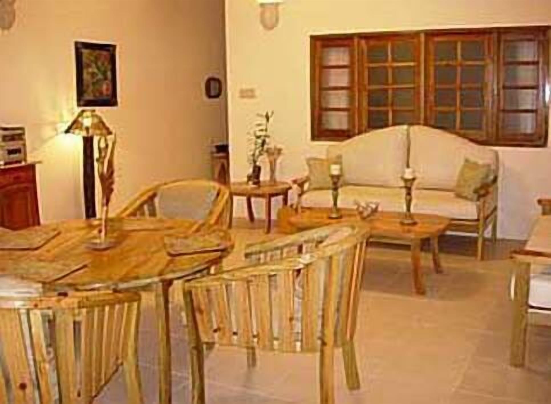 Un salon chaleureux avec une table à manger en bois, des chaises, un canapé et une fenêtre avec des rideaux.