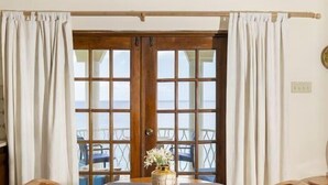 Un comedor con una mesa y sillas de madera, un florero con flores y vistas a través de un ventanal.