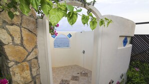 Baño con paredes de piedra, una zona de ducha, un ventanal con vistas y azulejos decorativos.