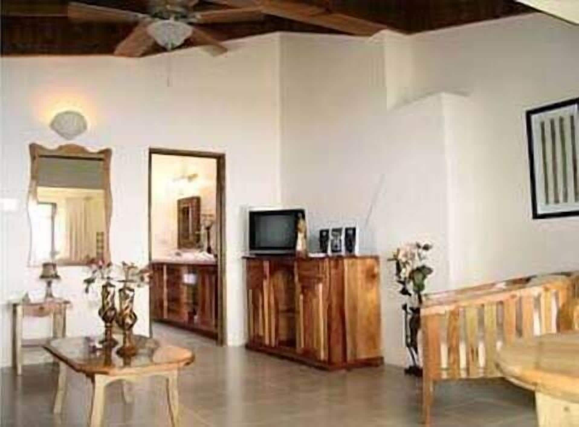 Una sala de estar con un mueble de madera, un televisor y un ventilador de techo.
