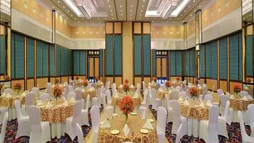 Un amplio salón de conferencias con mesas redondas, sillas blancas y centros de mesa florales.