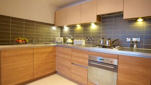 A modern kitchen with wooden cabinets, a stainless steel range, and a tiled backsplash.
