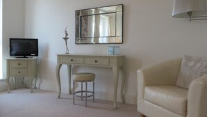 A room with a television on a small table, a desk with a chair, and a sofa.