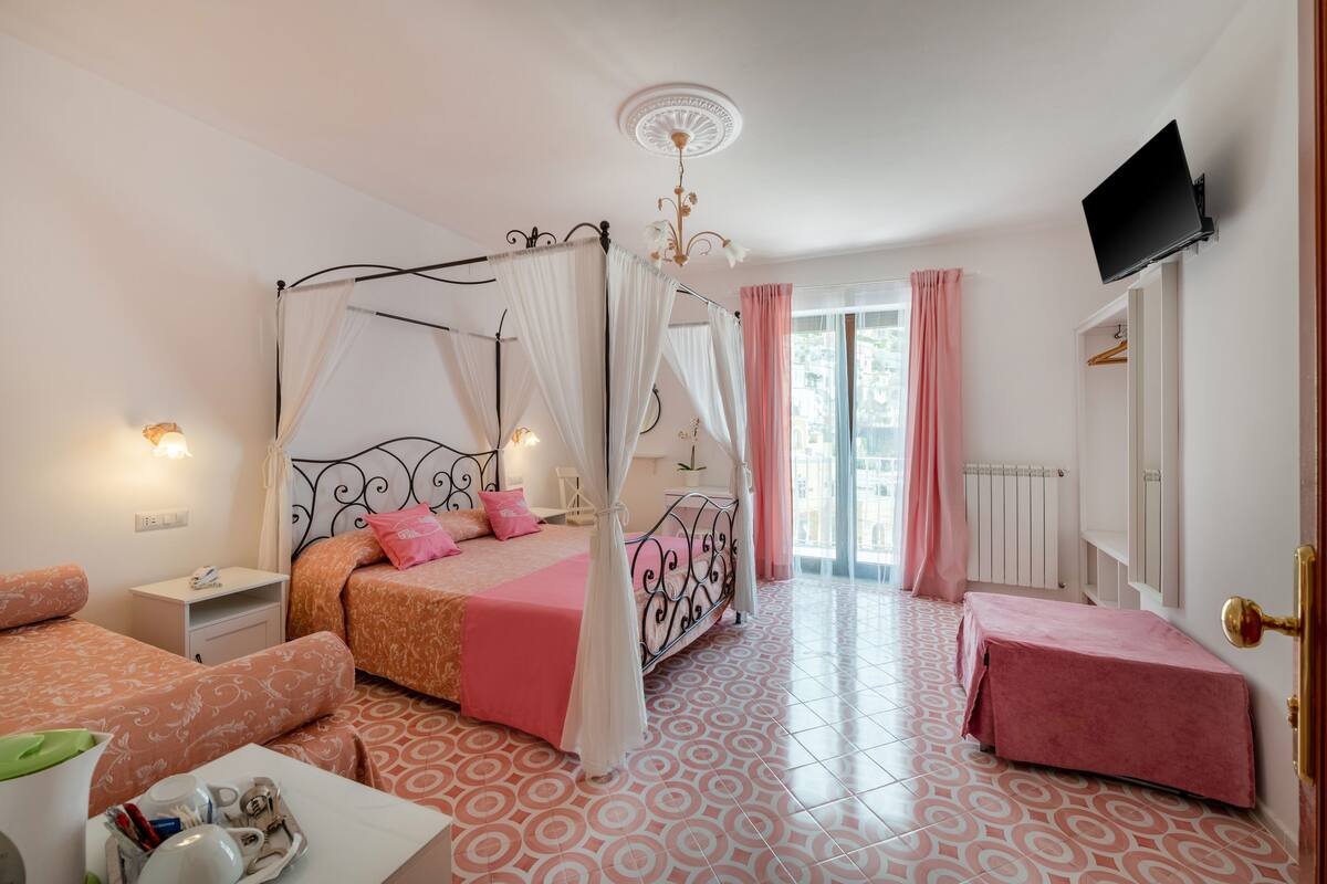 Un dormitorio con cama con dosel, una mesita de noche, una silla y una pequeña mesa con artículos de aseo.