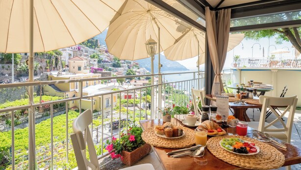 A balcony with a table set for breakfast, overlooking a scenic hillside.