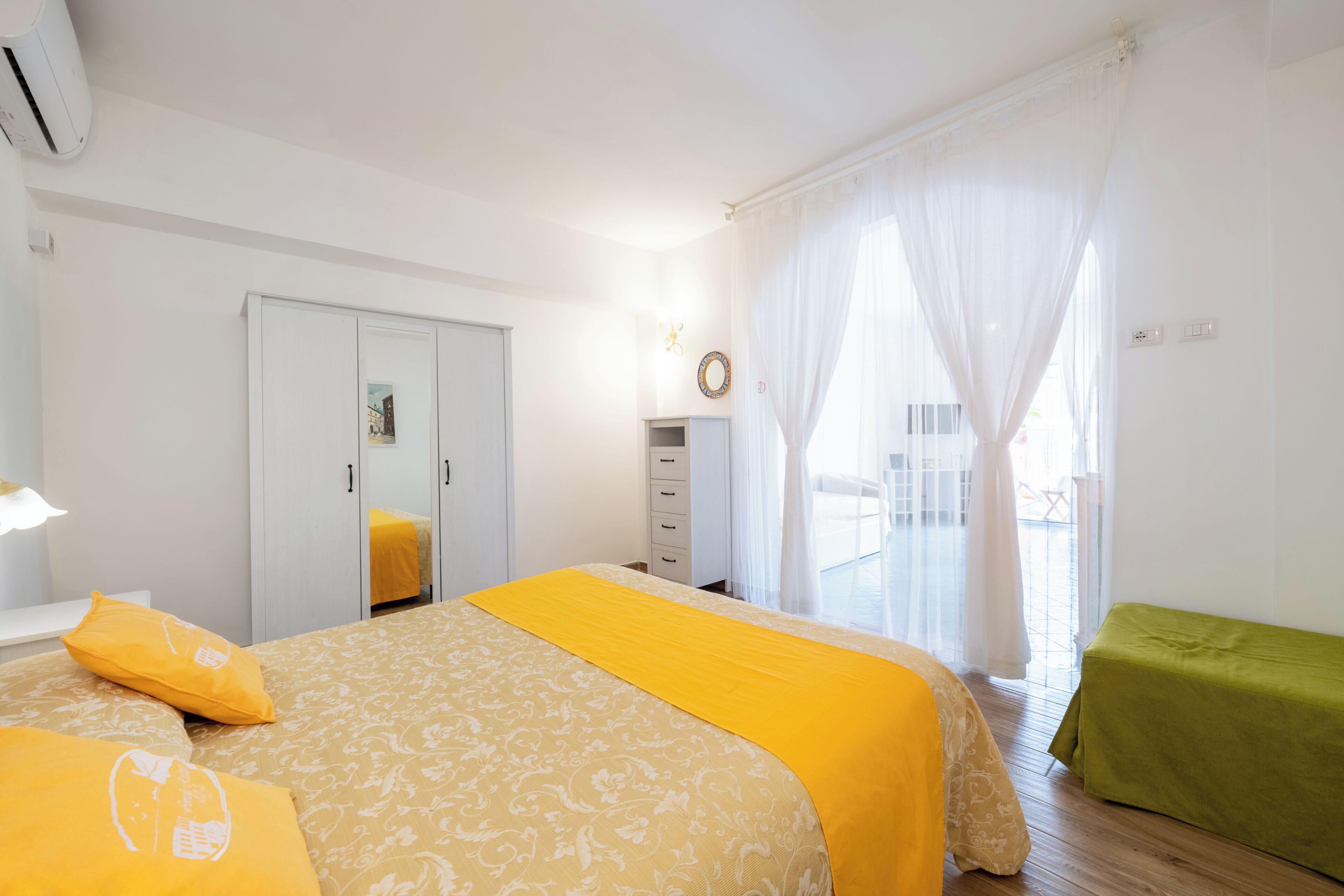 A bedroom with a bed, a wardrobe, a bedside table, and a window with curtains.