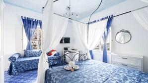 A bedroom with a bed, a bedside table, a TV, and a window with curtains.