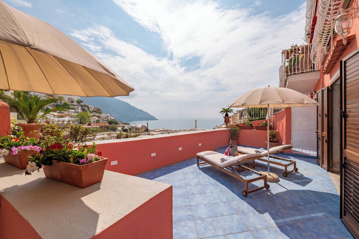 Terraza en la azotea con sillones de descanso, plantas en macetas y vistas al mar.