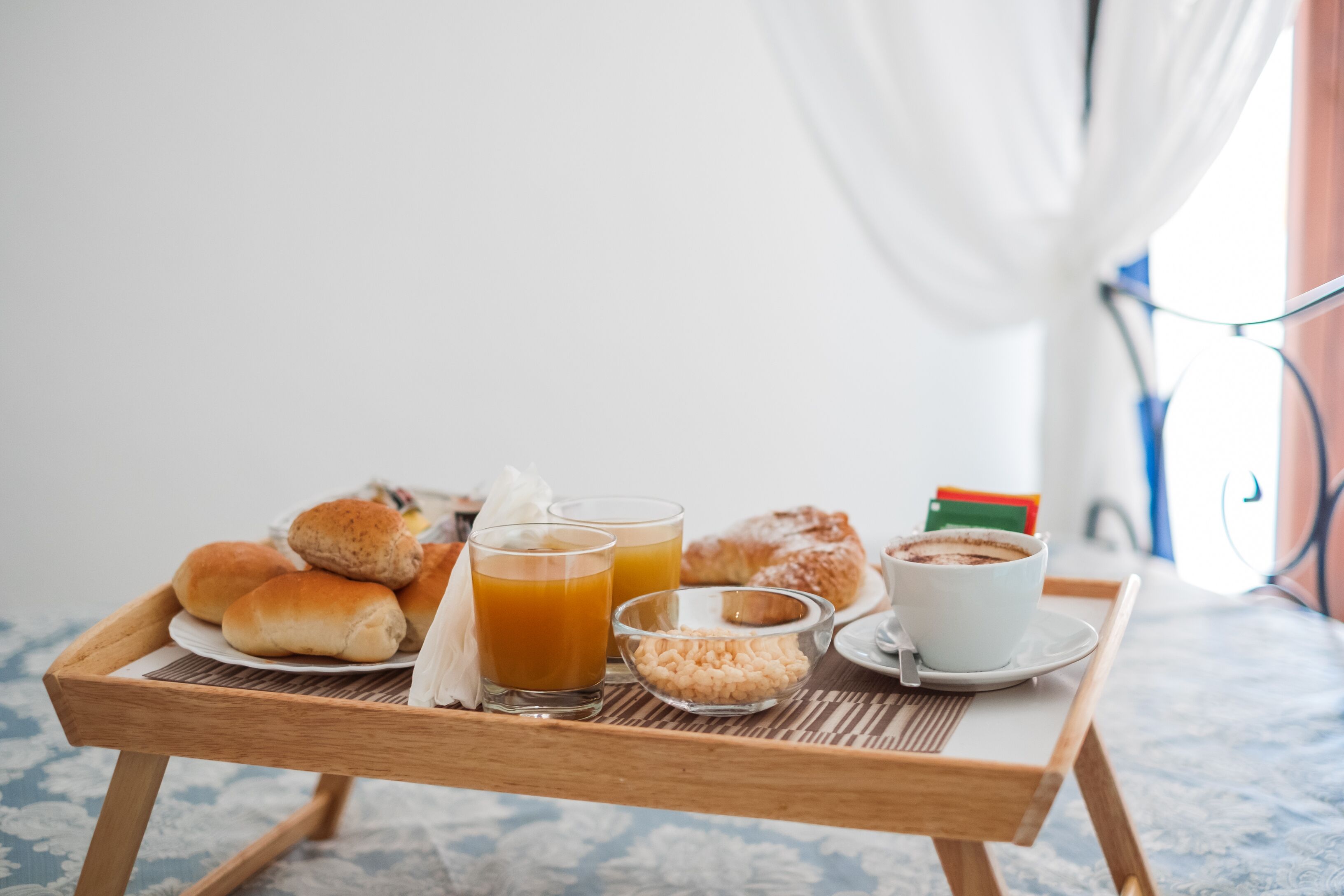 A tray with pastries, a glass of orange juice, and a cup of coffee on a patterned tablecloth.