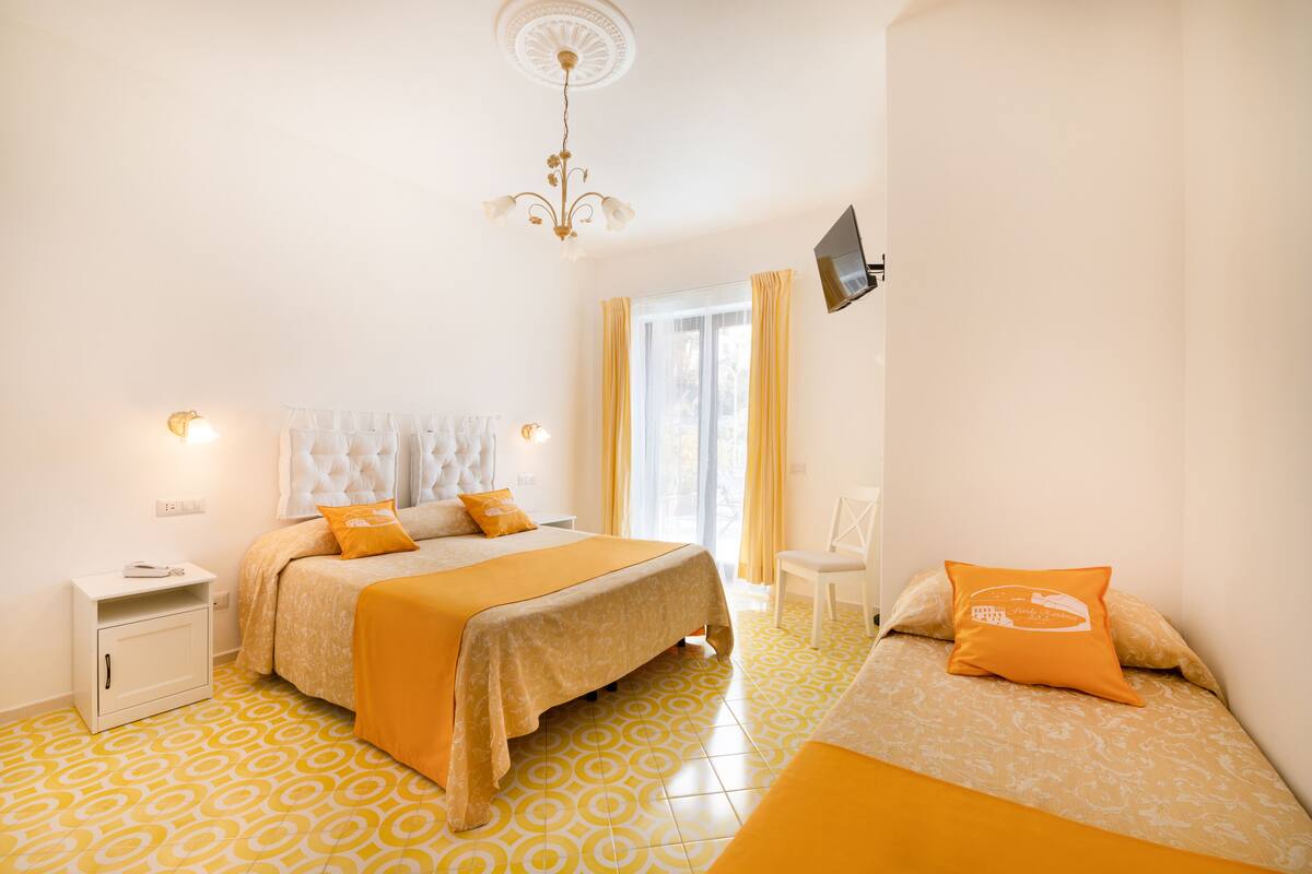 Un dormitorio con cama, mesita de noche y televisor en la pared.