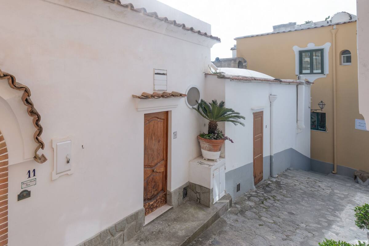 Una calle estrecha con un edificio blanco que presenta una puerta de madera grande y una ventana pequeña.
