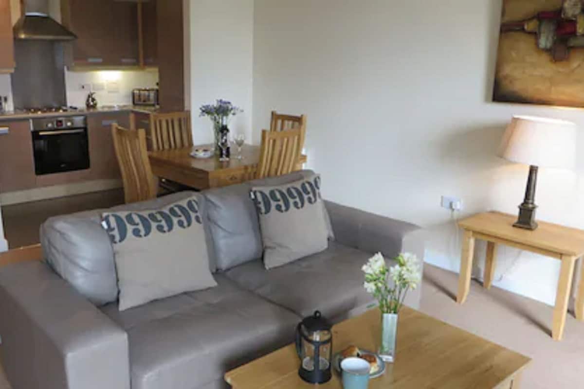 A living room with a grey sofa, a wooden coffee table, and a small table with a lamp.
