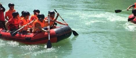 A group of people in a red inflatable raft on a river surrounded by greenery.
