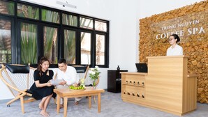 Un área de recepción con un escritorio de madera, sillas y una pared con un letrero que dice "TRUNG NGUYEN COFFEE SPA".