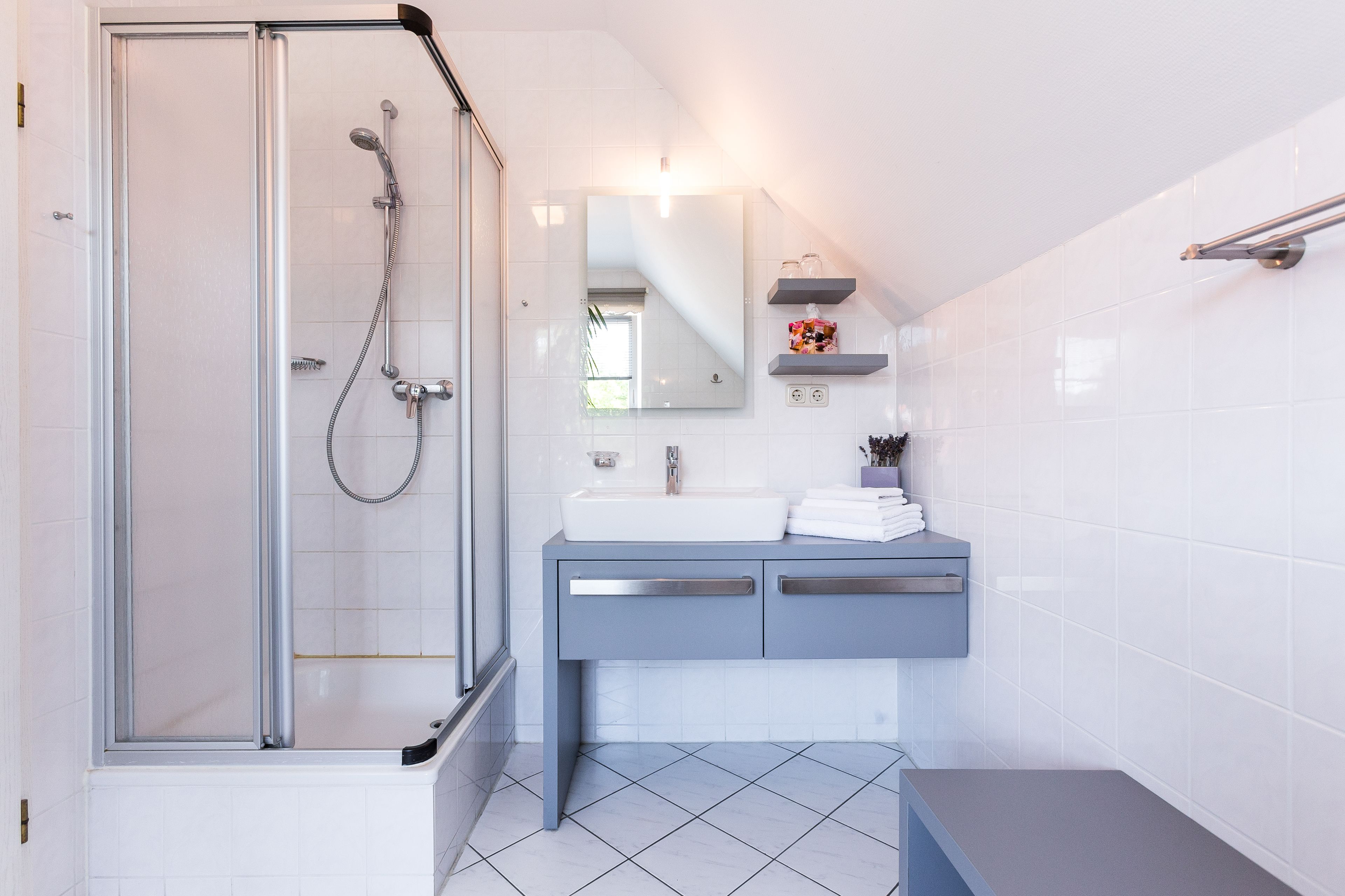 A modern bathroom with a glass-enclosed shower, a white sink, and a blue vanity.