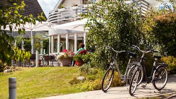 Um hotel com área de estar ao ar livre, bicicletas e um jardim bem cuidado.