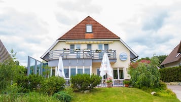 Een hotel met een rood pannendak, een balkon met buiten zitplaatsen en een bord dat aangeeft dat het een restaurant is.