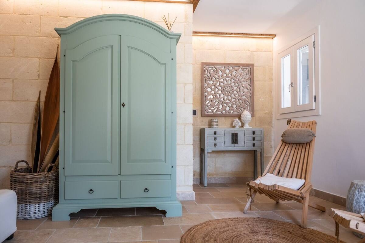 Une pièce comprenant un grand meuble bleu clair, un panier en osier, une chaise en bois et un élément décoratif mural.