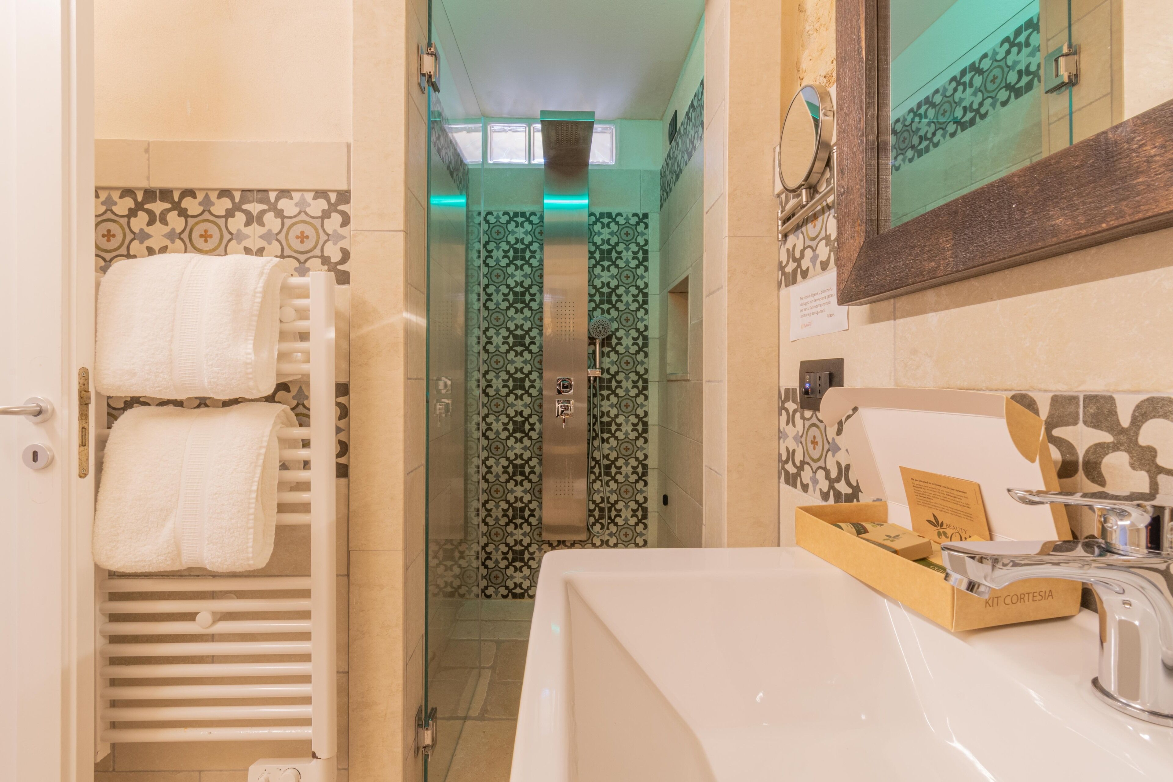 A bathroom with a white sink, a mirror, and a towel rack with two towels.