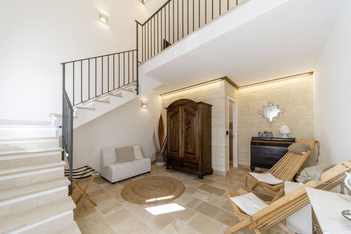 Un vaste espace de vie comprenant un escalier, un meuble en bois, un canapé et un fauteuil.