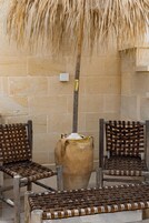 A seating area with woven chairs and a large vase.