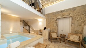 A spa area with a hot tub, wooden seating, and stone walls. - Masseria dei Monaci (Otranto)