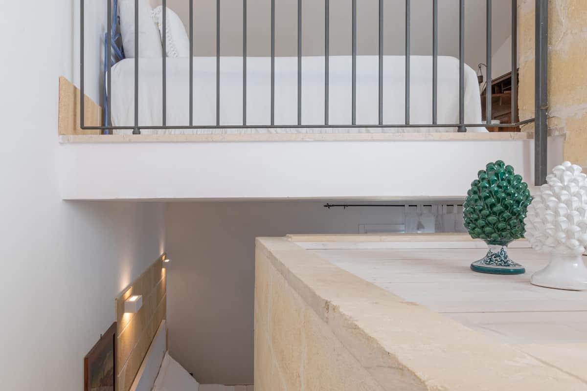 Une chambre avec un lit superposé, une petite table de chevet et une commode, ainsi qu’une plante décorative.