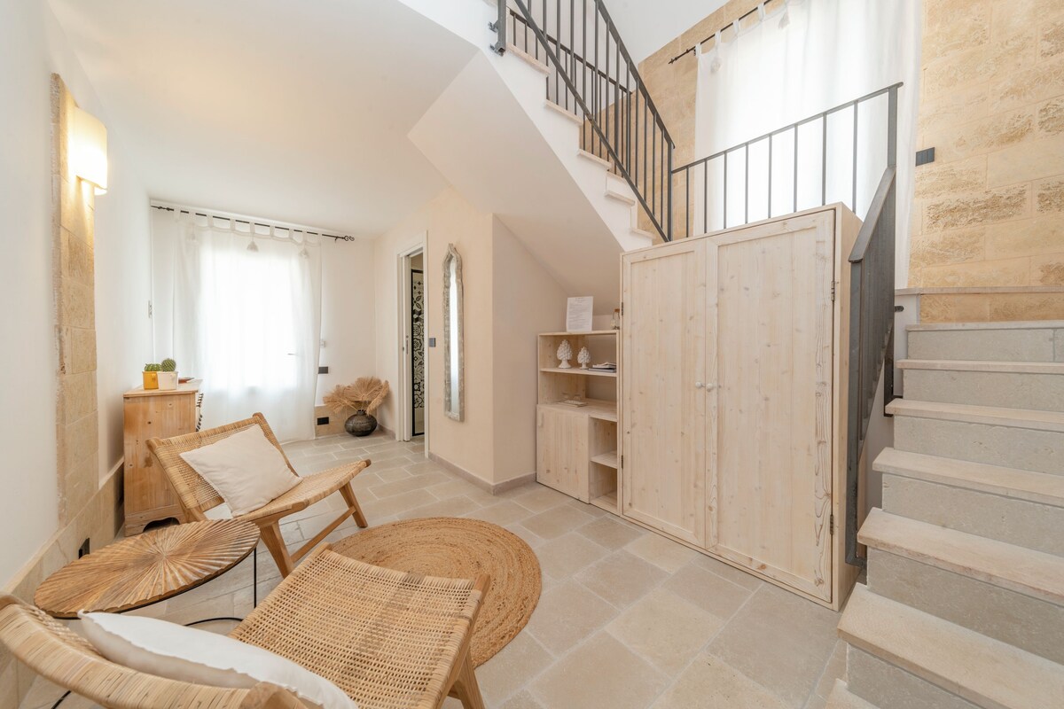 A spacious living area with a staircase, wicker furniture, and a wooden cabinet.