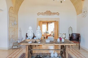 A spacious room with a wooden table set for dining, a leather armchair, and a decorative mirror.