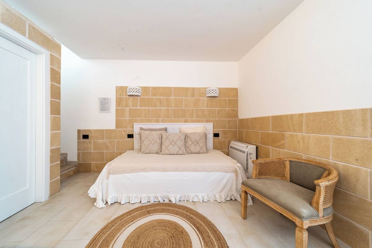 Une chambre à coucher comprenant un lit, une chaise, un radiateur et un mur orné d’un motif texturé.