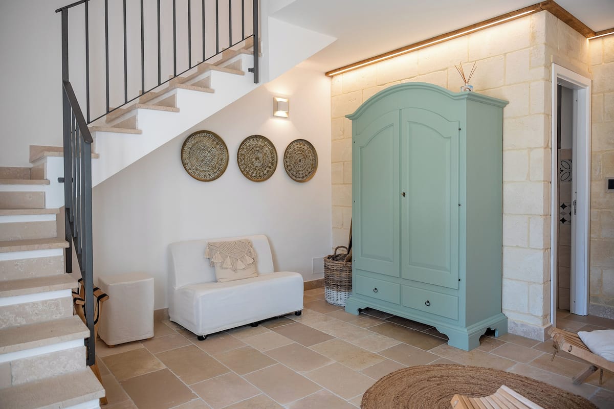 Un escalier menant à un palier où se trouvent un canapé blanc et un meuble bleu clair.