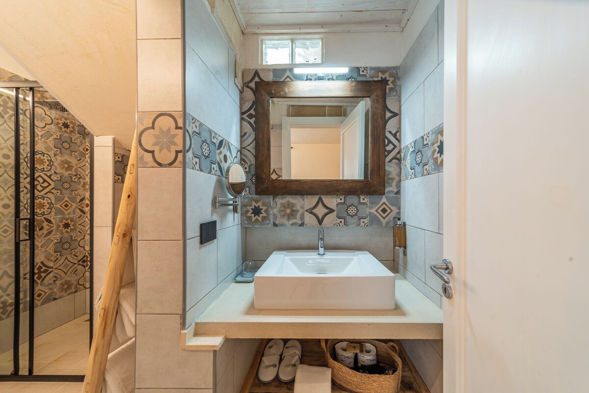 A bathroom with a white sink, a mirror, and patterned tiles.
