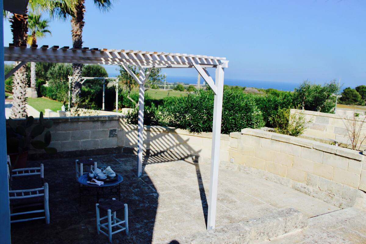 Une terrasse dotée d’une pergola, d’un espace salon extérieur et offrant une vue sur la mer.