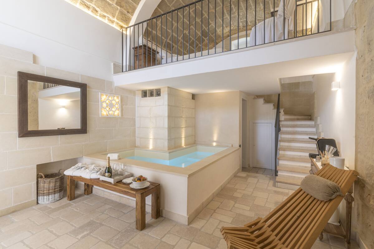 Un espace de bien-être comprenant une baignoire, un banc, une table avec des accessoires et un escalier.