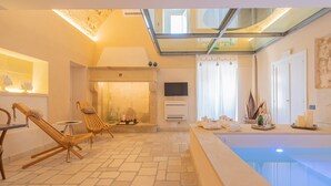 A spacious indoor area with a stone floor, a pool, and seating areas. - Masseria dei Monaci (Otranto)