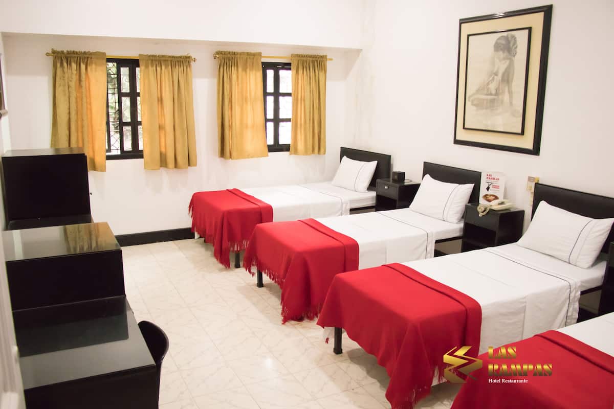 A hotel room with two beds, a TV, a desk, and a framed picture on the wall.