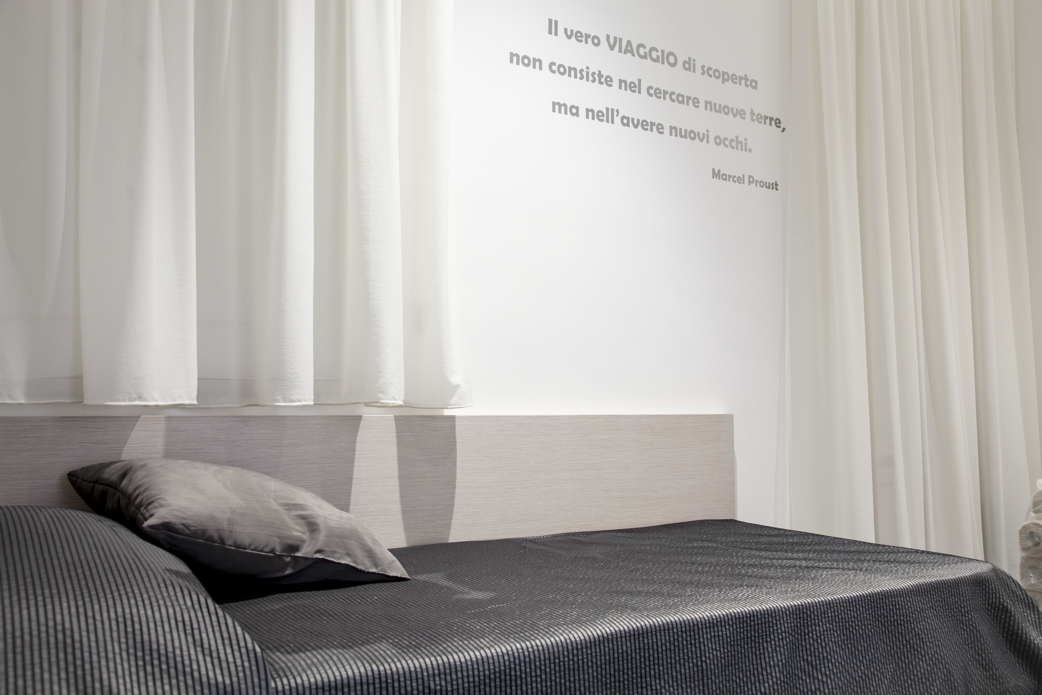 A modern bedroom with a bed, a pillow, and a quote on the wall.