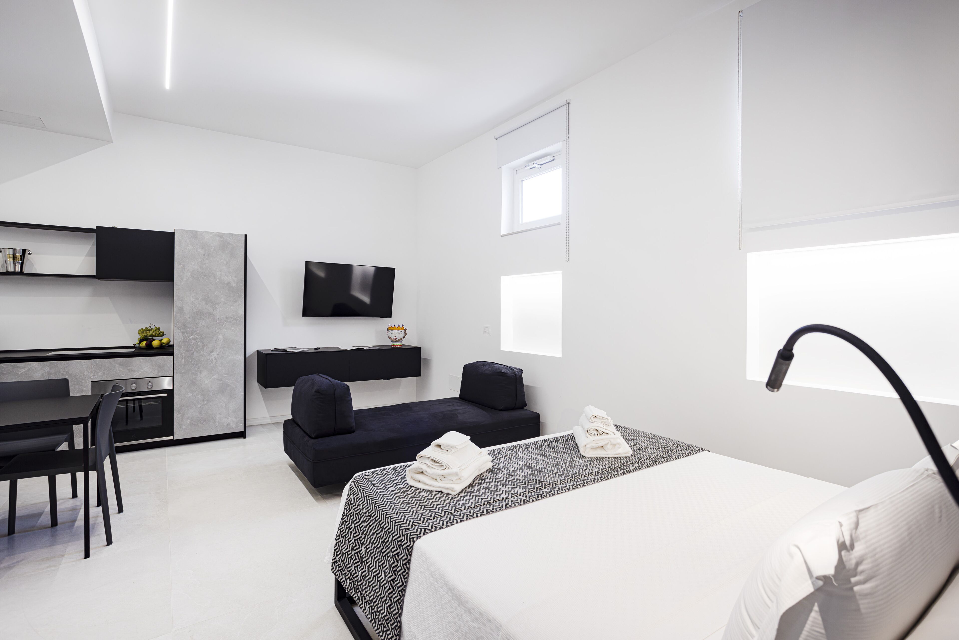 Una habitación de hotel moderna con cama, escritorio, sofá y televisor.